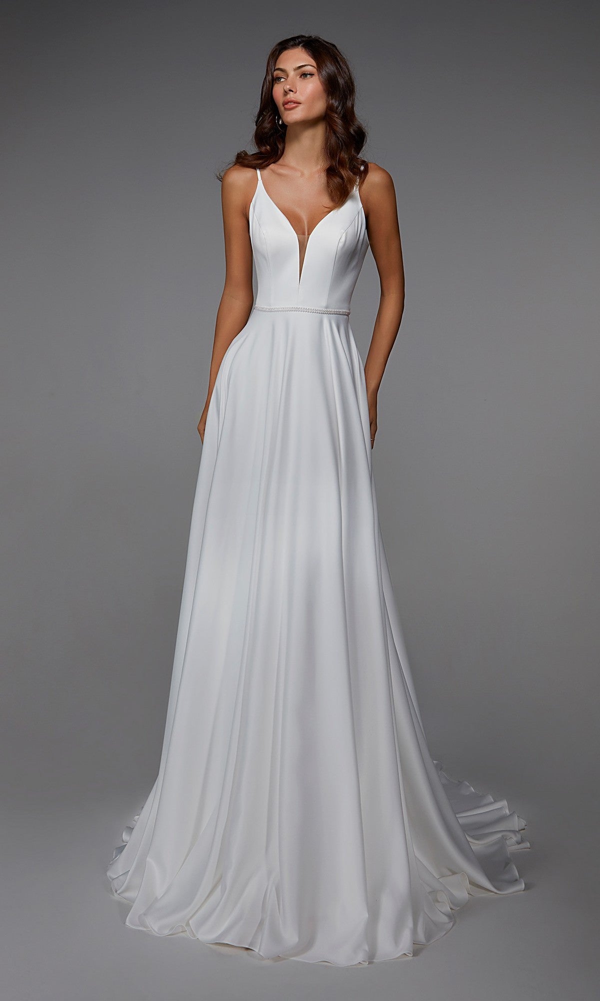 A woman stands against a plain gray background wearing the Alyce 7024, a sleeveless white satin long formal dress featuring a deep V-neckline and flowing A-line skirt.